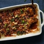 A baking pan of dumpling lasagna with a scooped slice with a spoon.