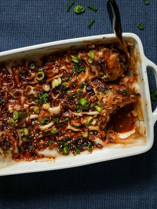 A baking pan of dumpling lasagna with a scooped slice with a spoon.