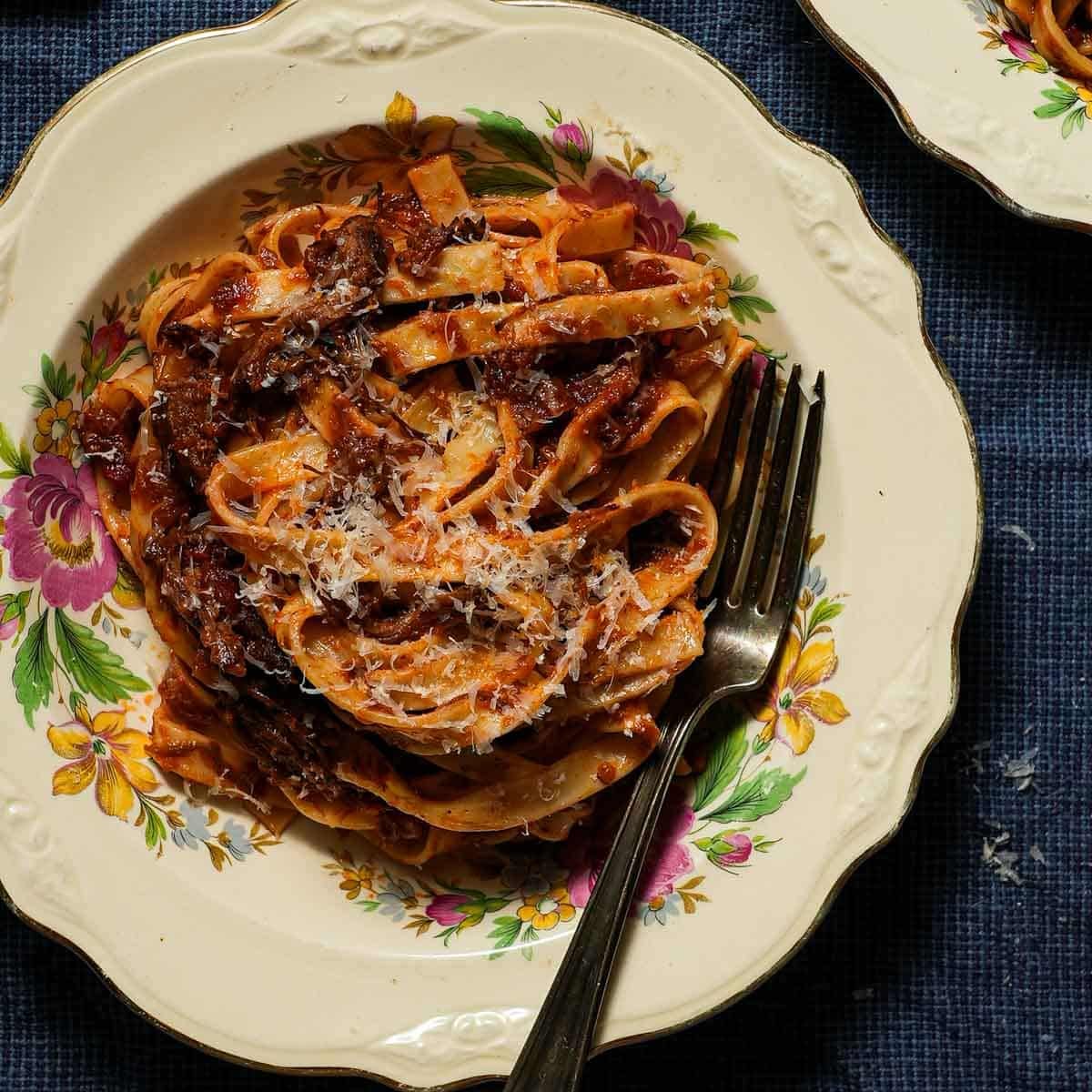 A bowl of braised short rib ragu with tagliatelle with a fork.