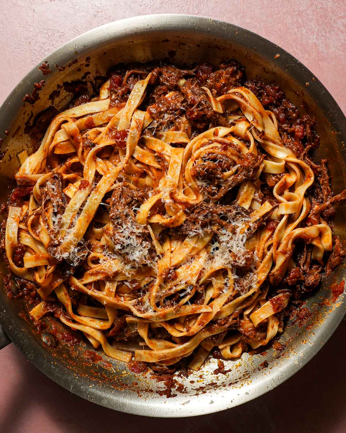 A skillet with tagliatelle pasta tossed with short rib ragu sauce.