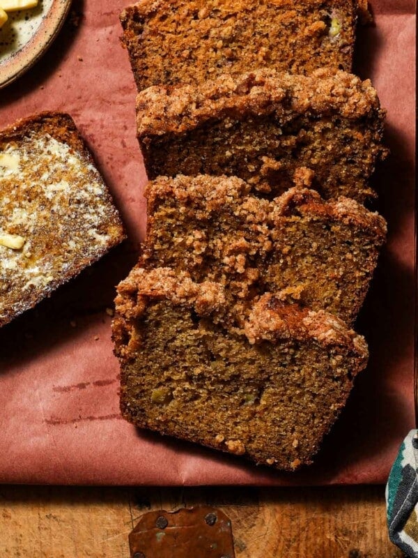 Slices of brown butter banana bread on a cutting board with butter.