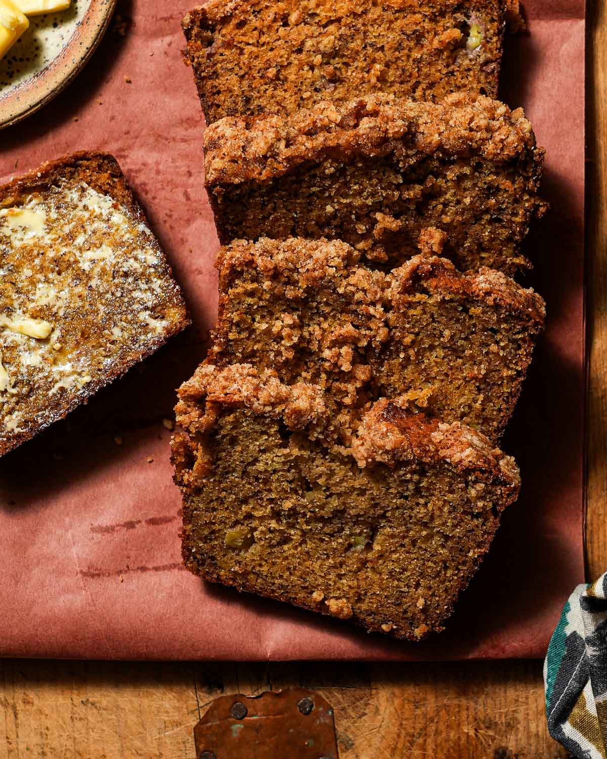 Slices of brown butter banana bread on a cutting board with butter.