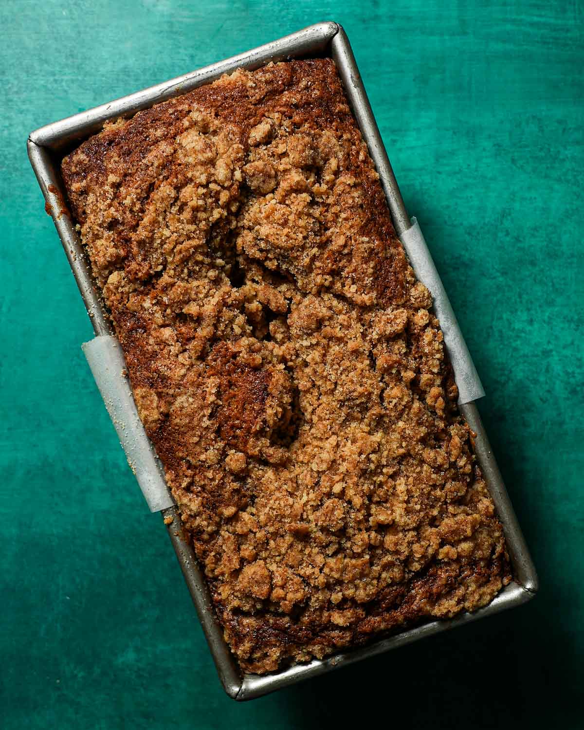 A loaf pan with brown butter banana bread batter topped with streusel after baking.