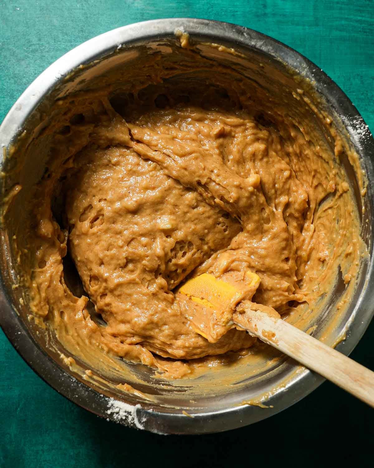 A bowl of banana bread batter being mixed with a yellow spatula.