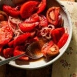 A bowl of marinated tomatoes with a spoon of juices.