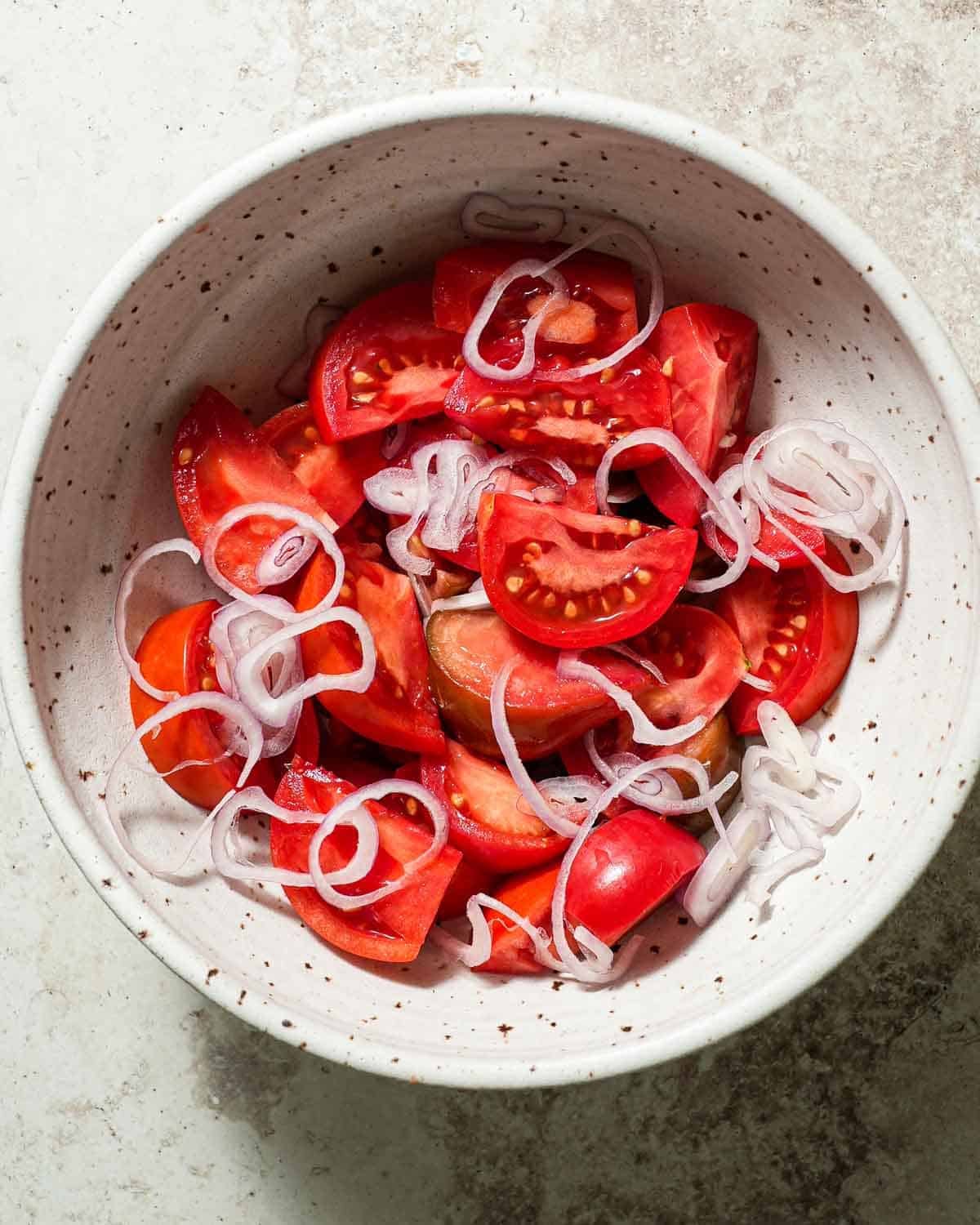 A bowl of quartered heirloom tomatoes and shallots.
