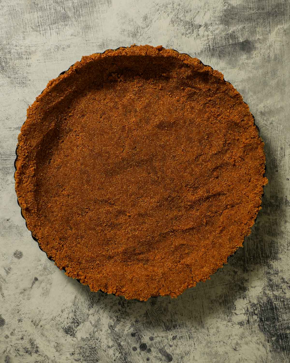 A pie pan with graham cracker crust that just got out of the oven.