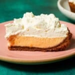 A pink plate with a Meyer lemon pie slice topped with whipped cream.