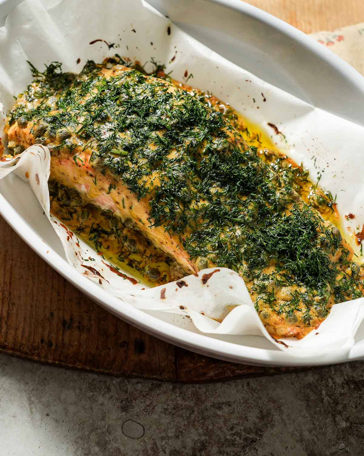 Dijon mustard dill salmon after being cooked in a baking dish with parchment paper.
