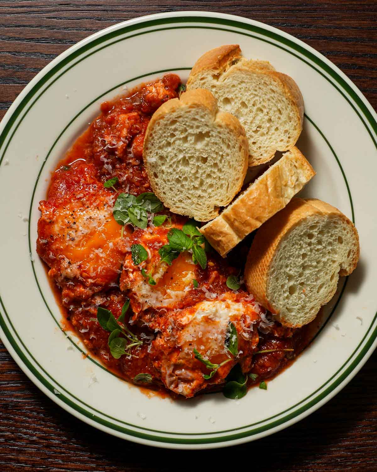 A plate of 3 eggs in purgatory with toasted baguette slices.