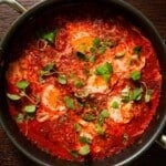 A skillet with spicy tomato sauce stewed with eggs, topped with oregano and parmesan.