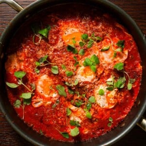 A skillet with spicy tomato sauce stewed with eggs, topped with oregano and parmesan.