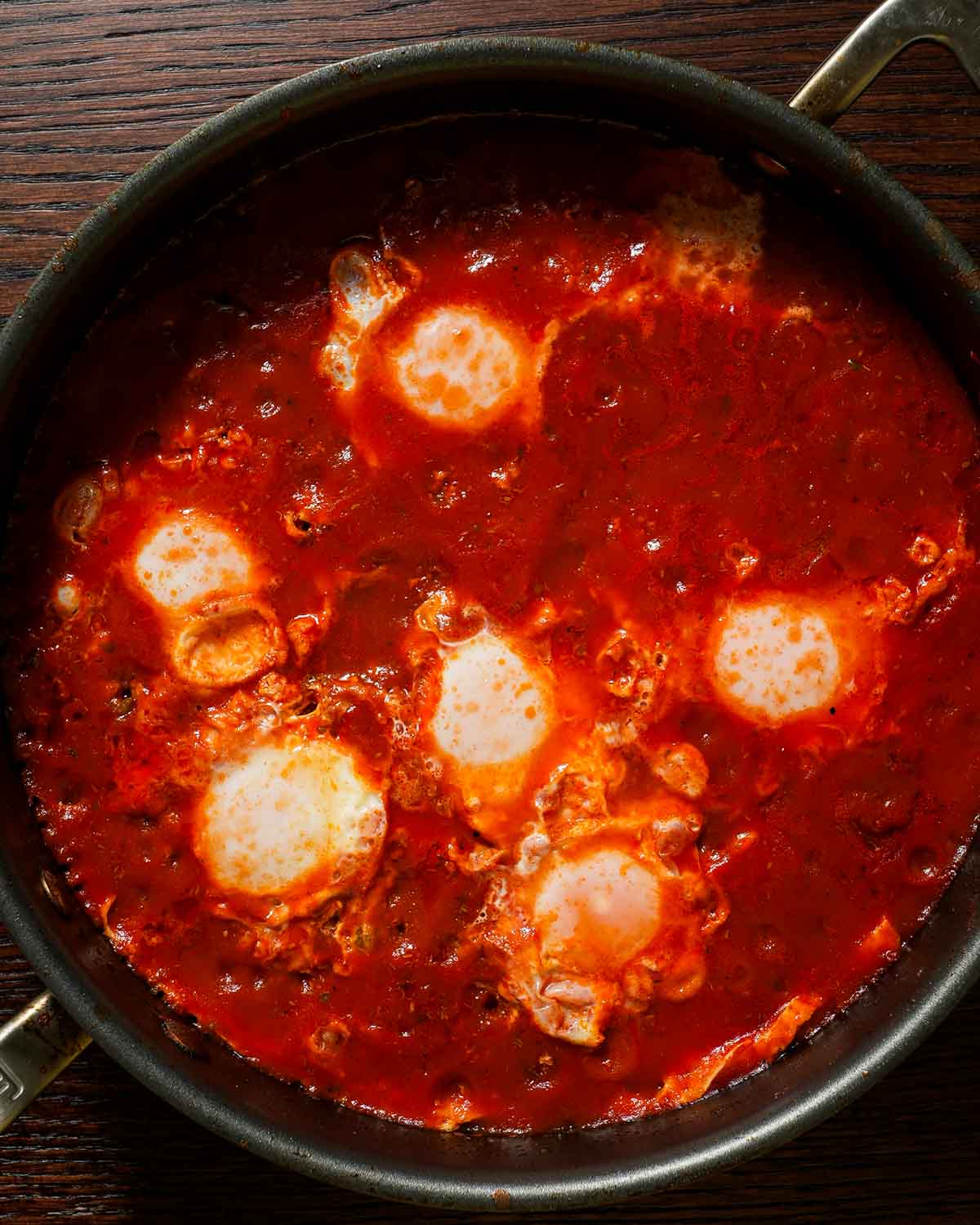 Poached eggs in tomato sauce in a large skillet, final dish of eggs in purgatory.