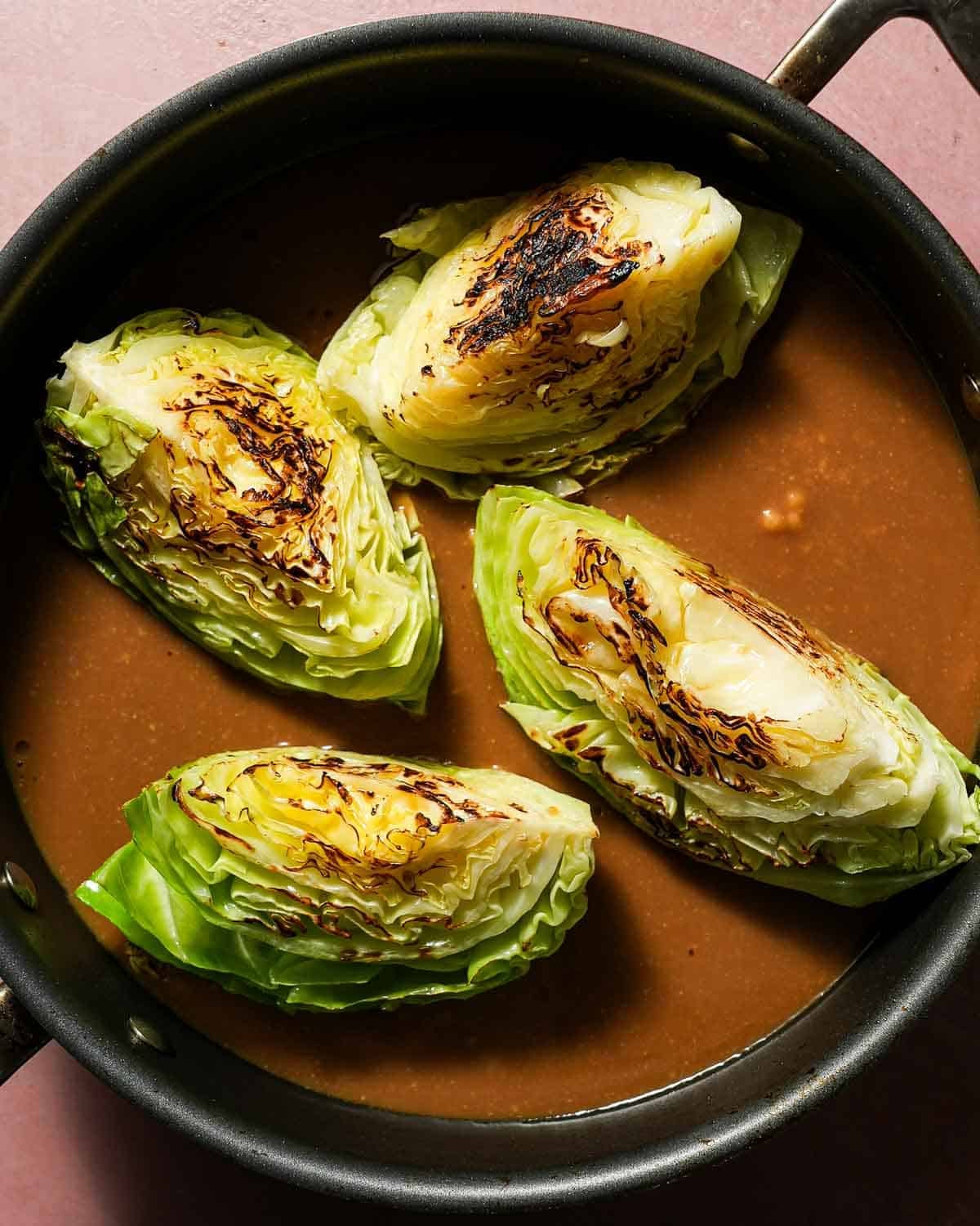 A skillet with seared cabbage and miso sauce in the skillet.