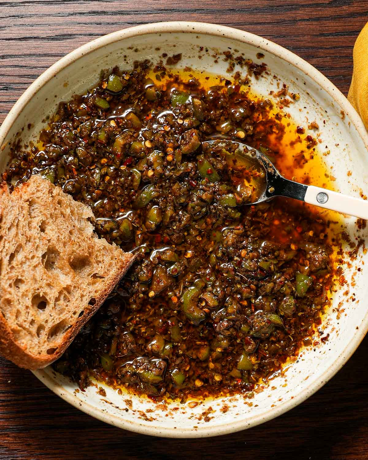 Bread dipping oil with a white bistro spoon and a toasted slice of bread.