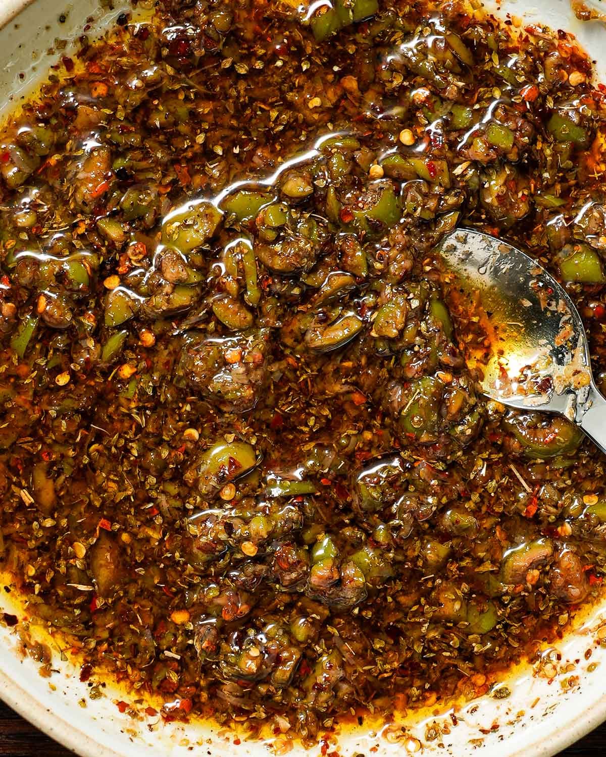 Mixed bread dipping oil with a spoon inside.