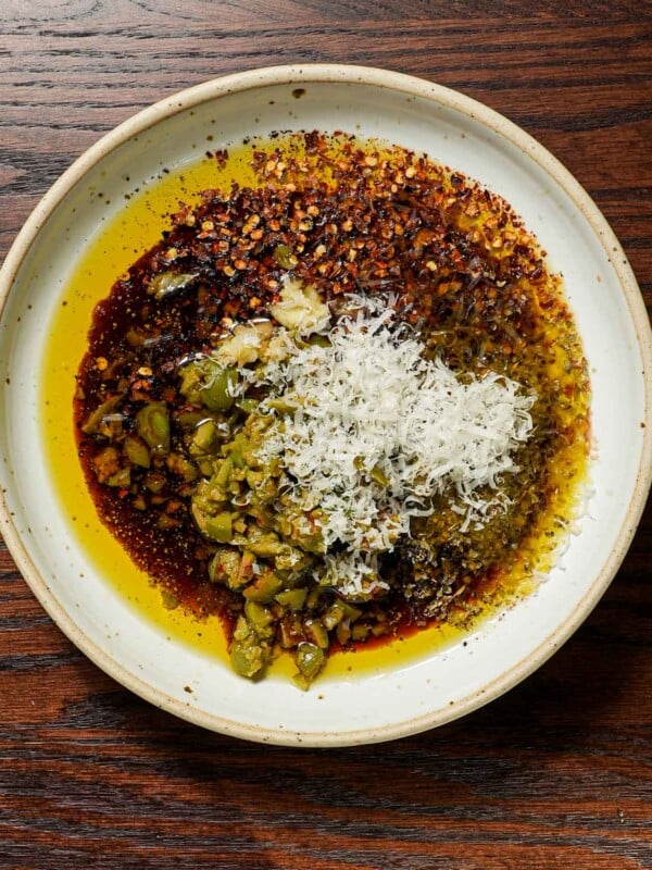 Ingredients in a bowl of bread dipping oil with olives and balsamic vinegar.