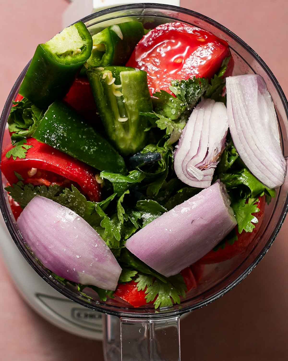 A food processor making heirloom tomato salsa with shallots and jalapenos.