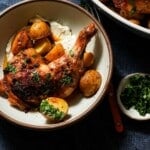 A shallow bowl of greek lemon chicken and potatoes with greek yogurt and parsley.