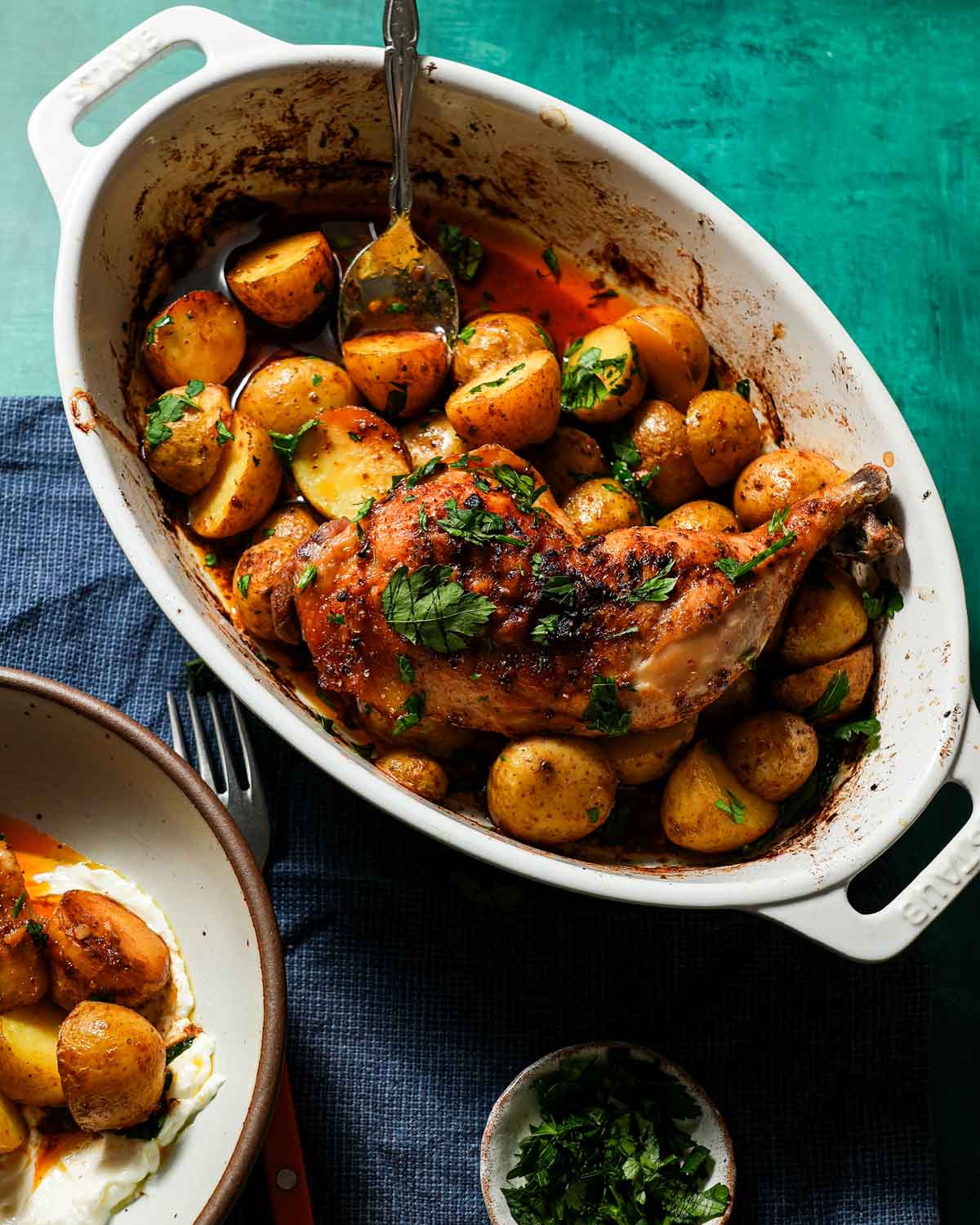 A baking dish of baked chicken and potatoes with parsley.