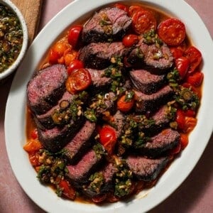 A platter of hanger steak with cherry tomatoes with a ginger scallion ponzu sauce.