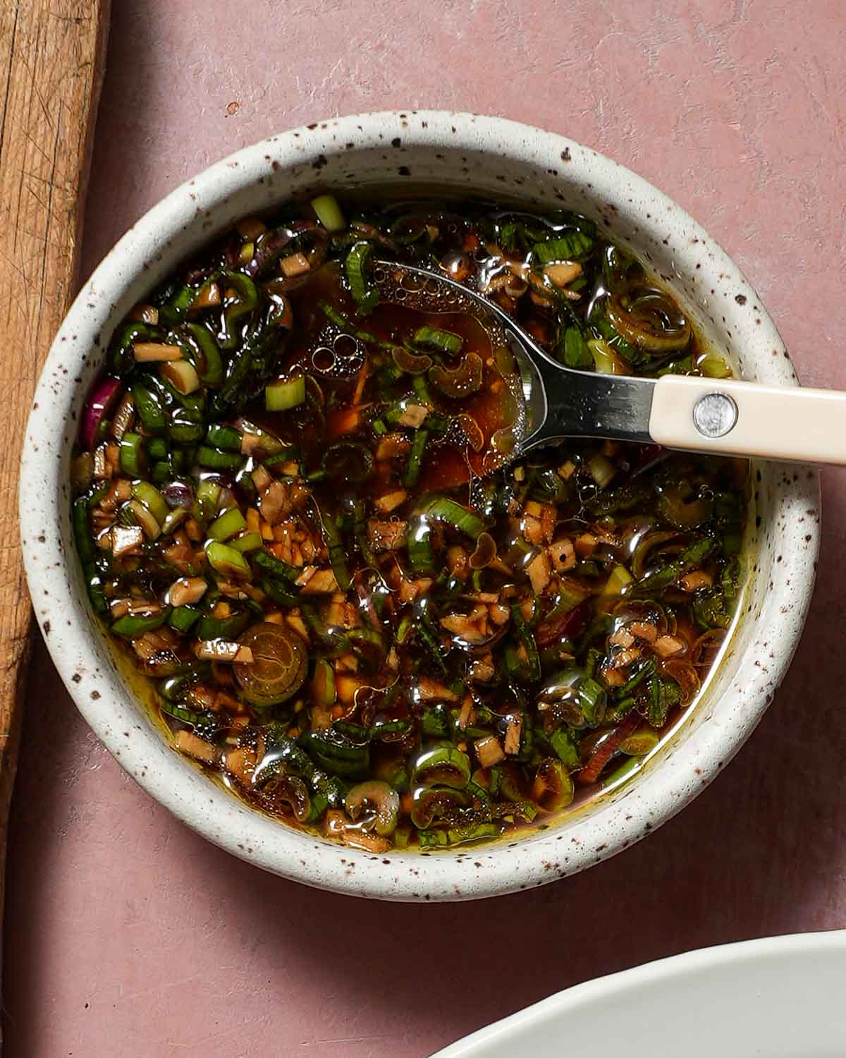 A bowl of ginger-scallion ponzu sauce with a white bistro spoon.