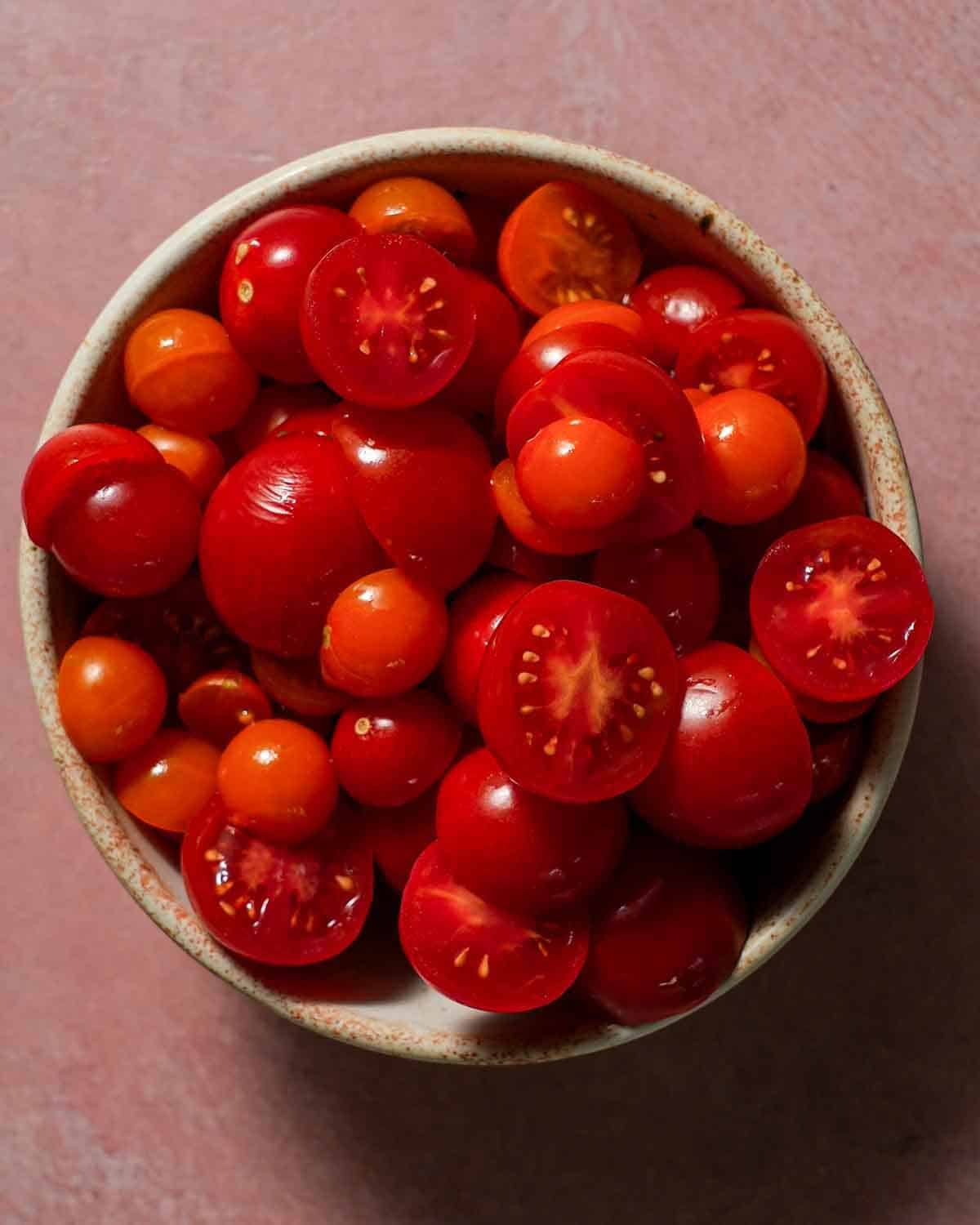 Cherry tomatoes in a bowl that have been halved.