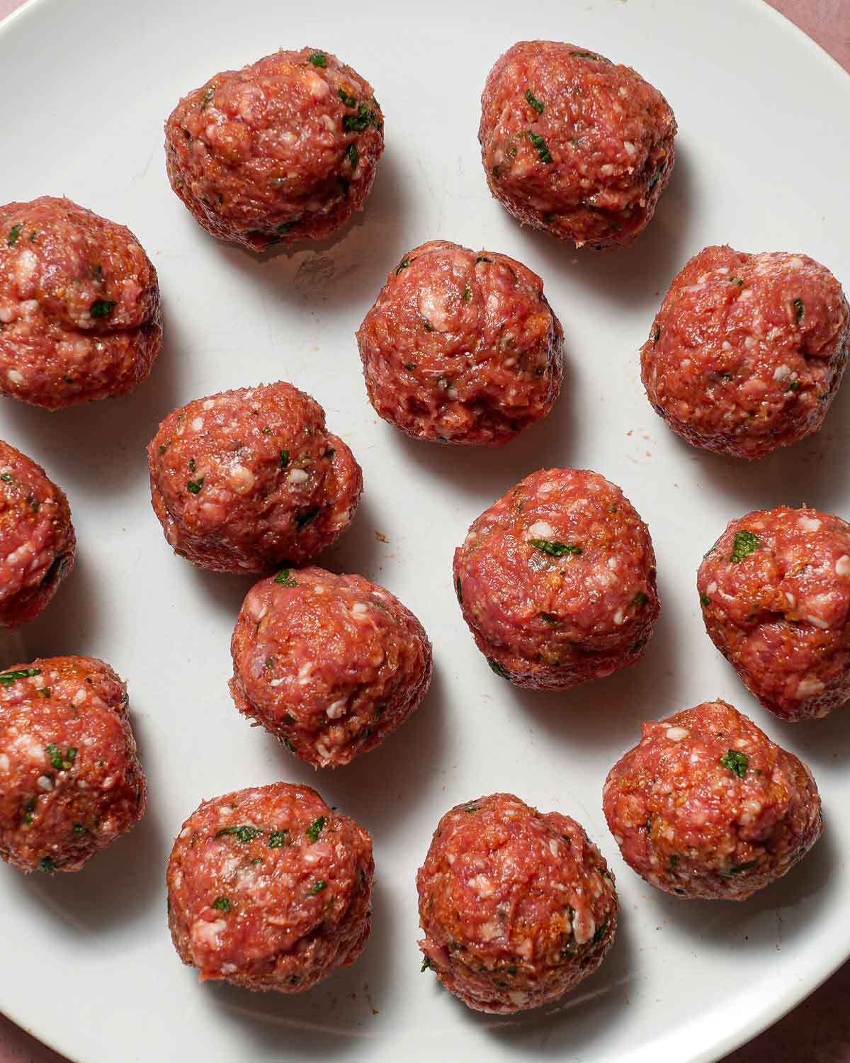 A plate of raw lamb meatballs ready to be simmered in tomato sauce.