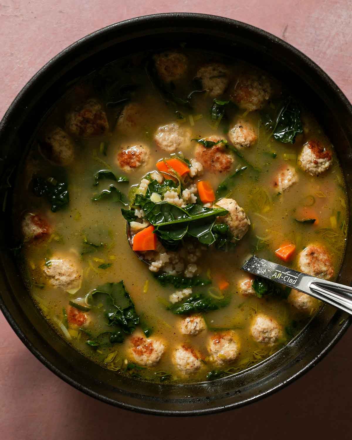 A large pot of Italian wedding soup with a All-Clad soup ladle.