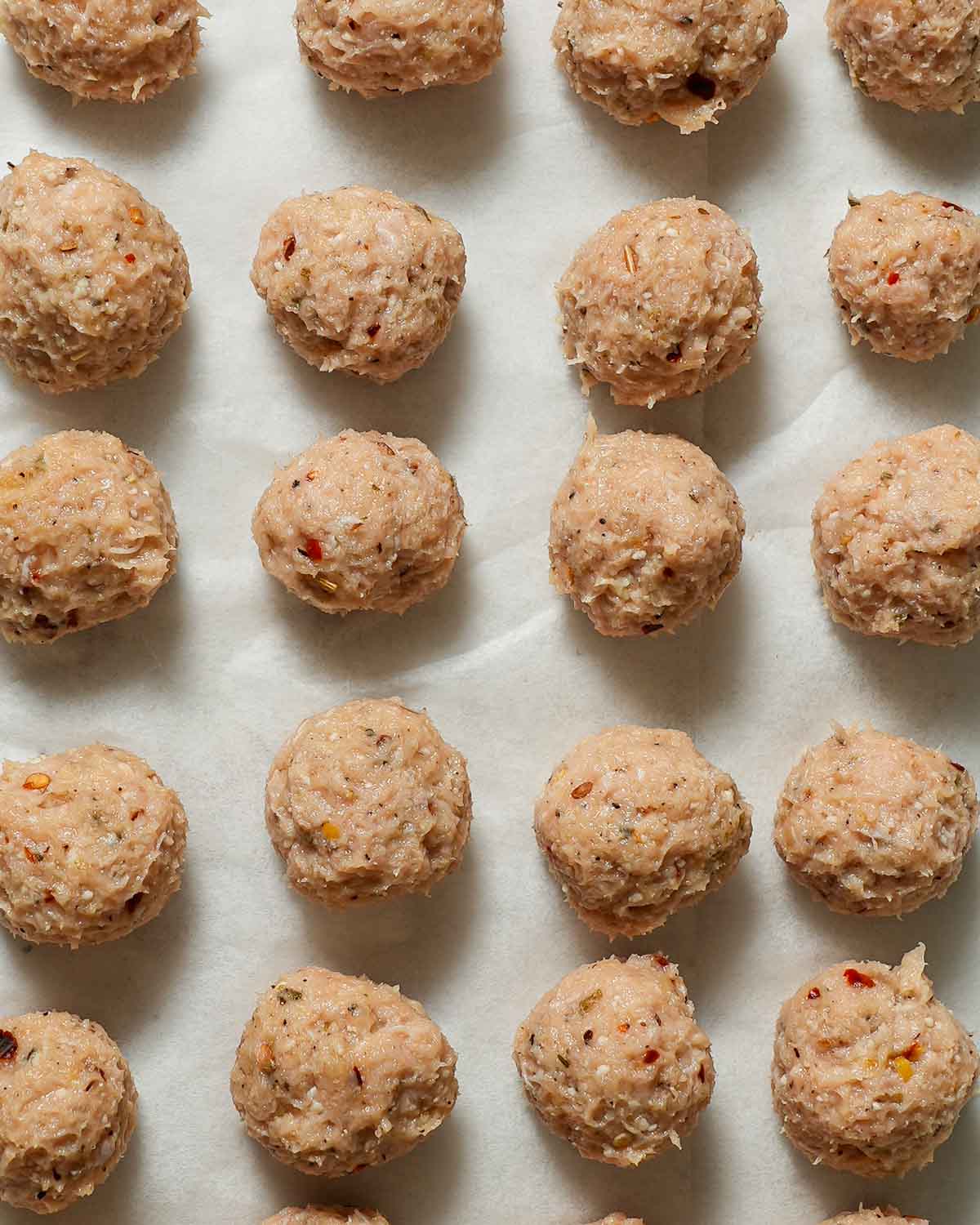 Mini chicken meatballs on parchment paper.