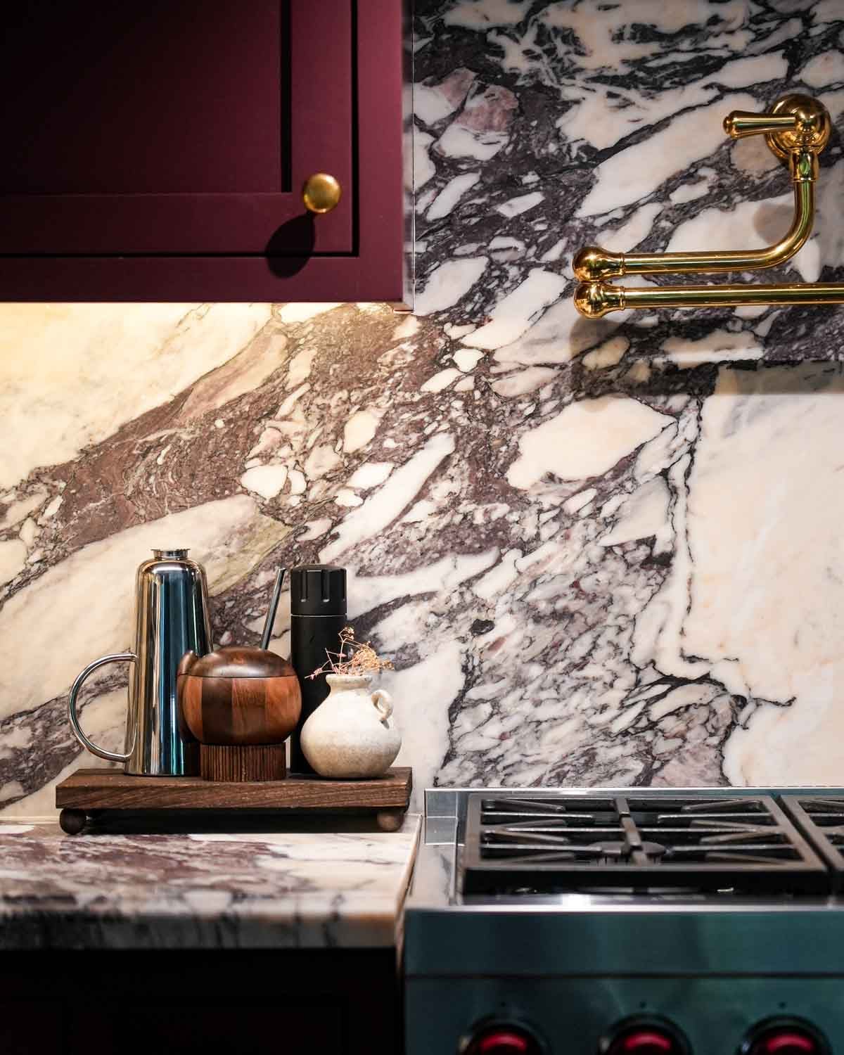 Kitchen countertops with a pot filler, marble, range with a brown mini table with olive oil, salt and pepper on top.