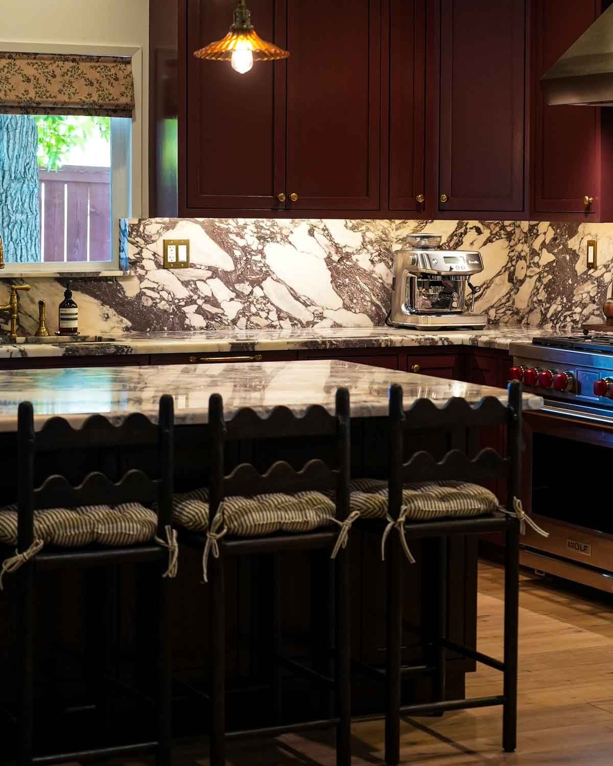 Kitchen renovation with walnut stools, burgundy cabinets and marble.