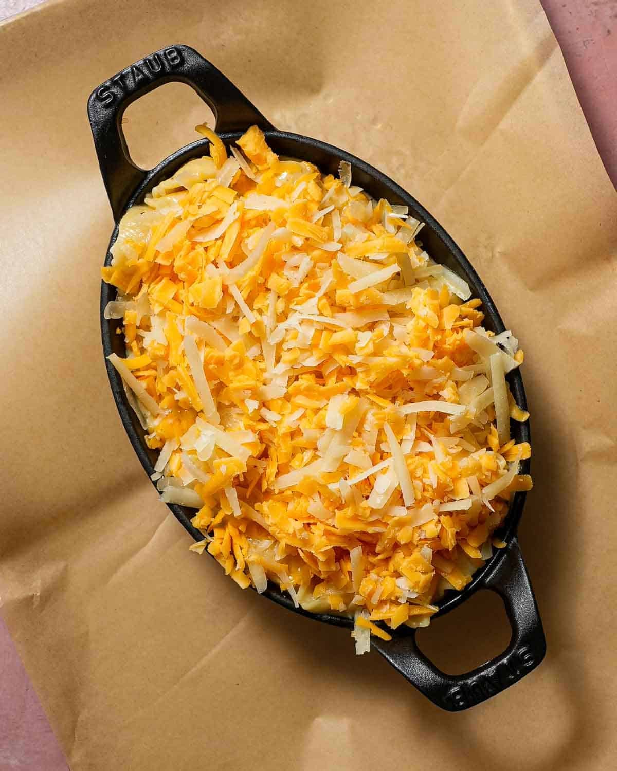 A baking dish with mac and cheese topped with cheese ready to be baked.
