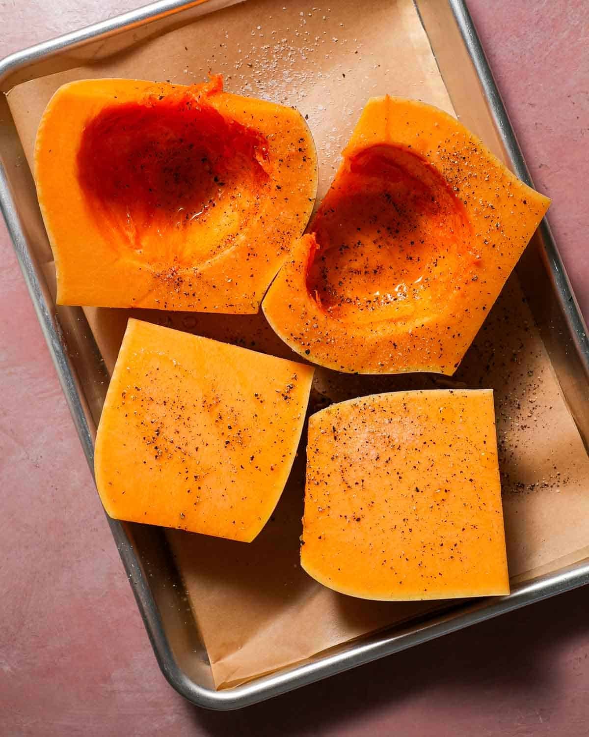 Butternut squash on a baking sheet with olive oil, salt, and pepper.